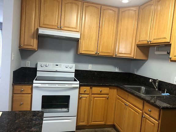Kitchen has bottom freezer refrigerator, glass top oven/stove, and a vented hood.