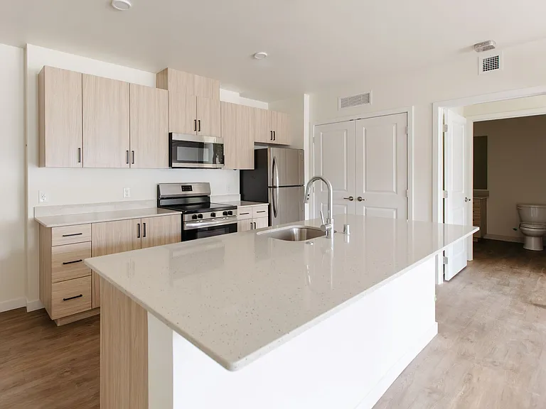 Finishing touches are going in at The Elowen in Lacey, Washington. This bright apartment kitchen features a spacious island, stainless steel appliances, and plenty of storage.