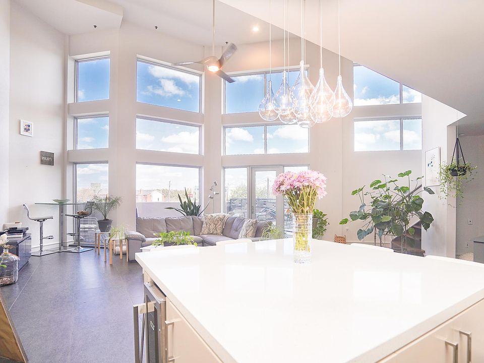 View from the kitchen facing the living room and the stunning wall of windows in the living room. Windows have privacy tinting and face north. Note the modern pendant lighting and the wine fridge. Great storage in the island including hidden cabinets.