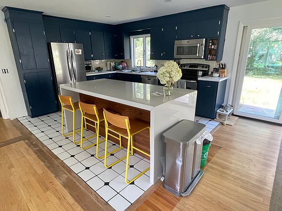 Open concept Kitchen, with large waterfall island, new fridge, fresh paint and new countertops.