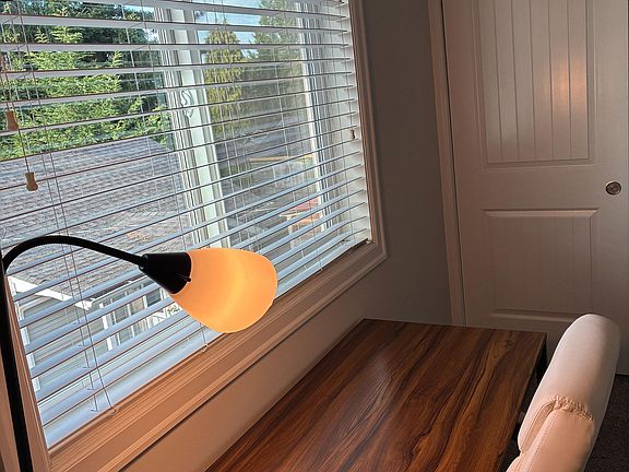 Dedicated workstation nook with a large window, blinds, and desk spaceideal for remote work or study.