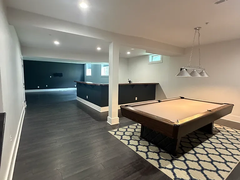 Basement ready for entertainment full of light and a pool table.