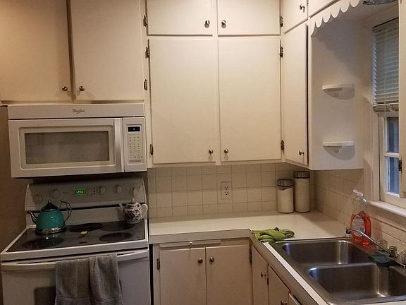 Kitchen w/white cabinetry, updated hardware, refrigerator, dishwasher, built-in microwave, and self cleaning range.