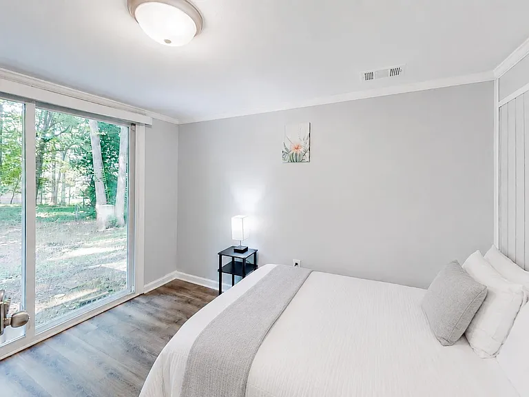 Bedroom features a large sliding glass door for easy outdoor access, plus a furnished sleeping area and bedside lighting.