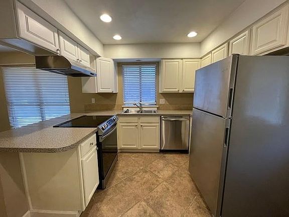 Kitchen featuring kitchen peninsula, white cabinetry, sink, and appliances with stainless steel finishes