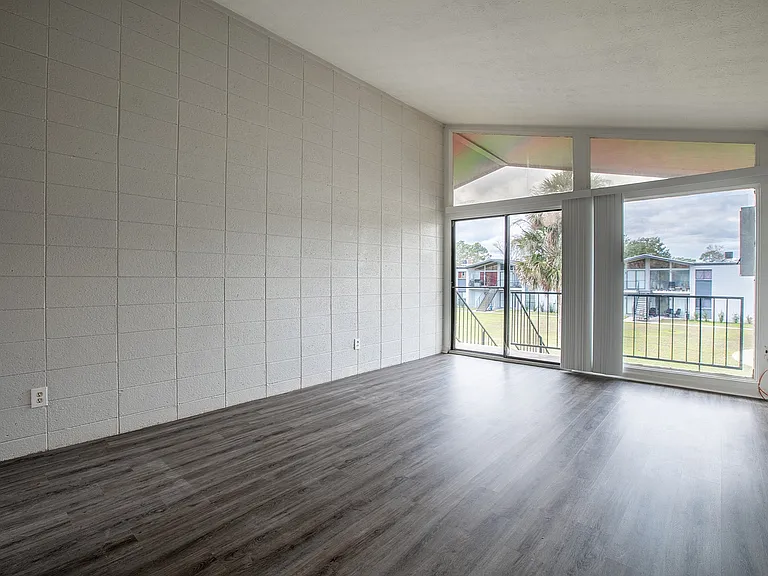 Bright and airy living room with modern flooring, large windows, and a serene outdoor view.