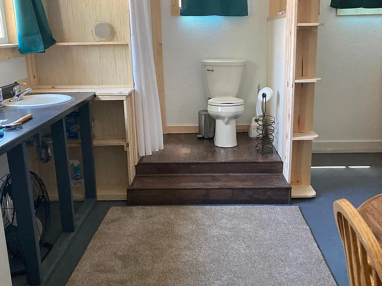 close up of the toilet (shower to the left behind the white curtain) - this photo was taken before the wooden door was installed.