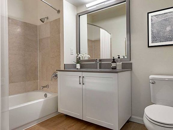 Newly renovated Finish Package IV baths with grey quartz countertops, white cabinetry, and hard surface flooring