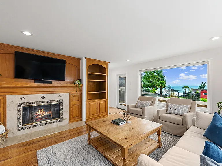 View Living Room with gas fireplace, built-in bookshelves and hardwood floors