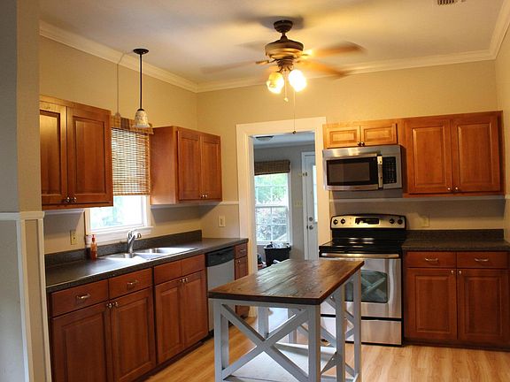 Kitchen: cook top, oven and microwave. Dishwasher near sink. Laundry room through the doorway. Two ceiling fans.