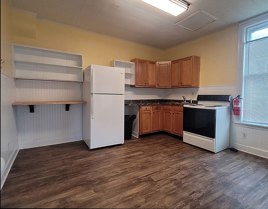 Large eat-in kitchen featuring new flooring, paint, wainscoting, and shelving.
