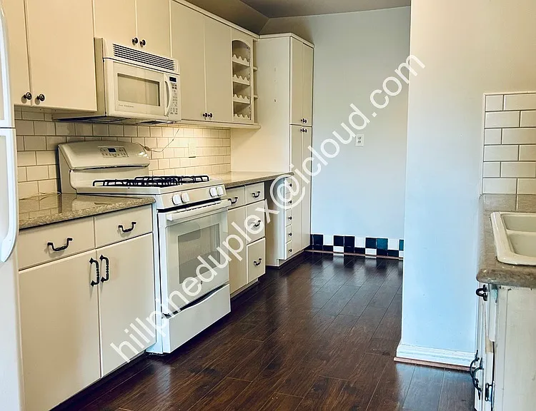 Spacious kitchen quartz counter tops with gas stove, built-in microwave, fridge, dishwasher, garbage disposal, and pantry