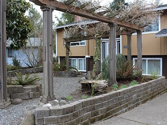 Gardener's paradise, front courtyard with stone planters and Wisteria arbor.
