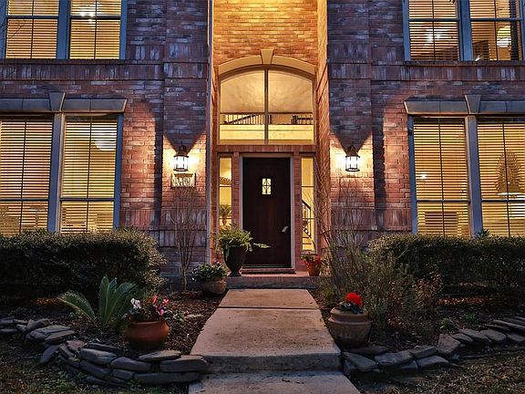 Brick with coined detail enhancing the windows and rock lined landscaping with sprinklers. New porch lanterns in updated deign.
