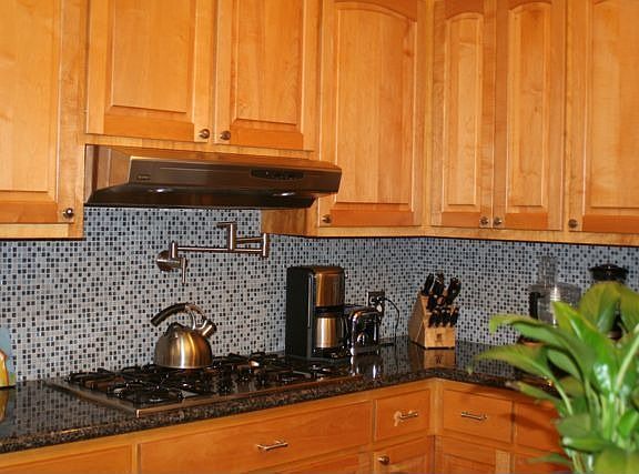 Pot filler above gas range set against updated backsplash.