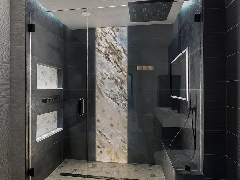 Spa-style bathroom with a large glass walk-in shower, rainfall showerhead, and built-in niches for easy storage.