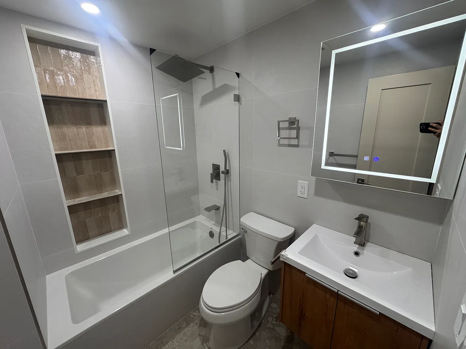 Stylishly renovated bathroom featuring a rainfall shower and built-in shelving.