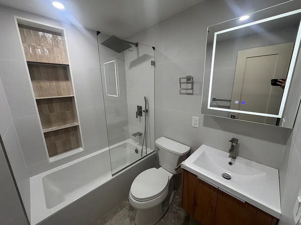 Stylishly renovated bathroom featuring a rainfall shower and built-in shelving.