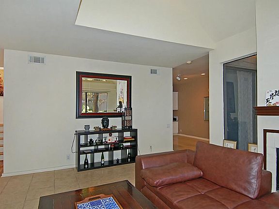 Tall ceilings and a fireplace in this living space, open to the breakfast/dining room.  Note the wood stairway on the left.