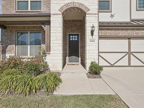 View of exterior entry featuring brick siding, stone siding, covered porch, and an attached garage