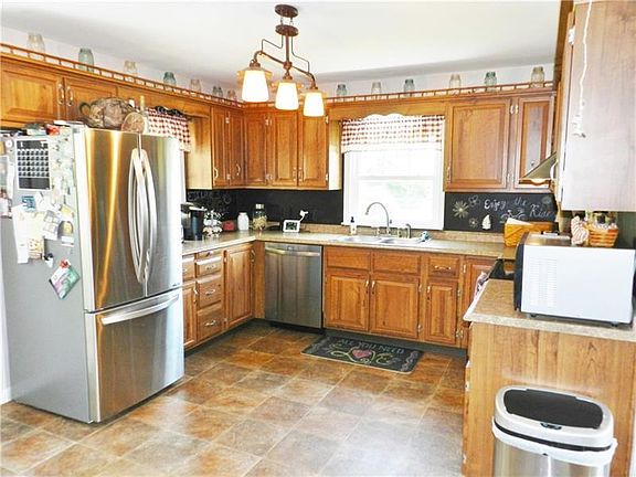 Cheerful kitchen with stainless steel appliances, new lighting chalkboard backsplash.