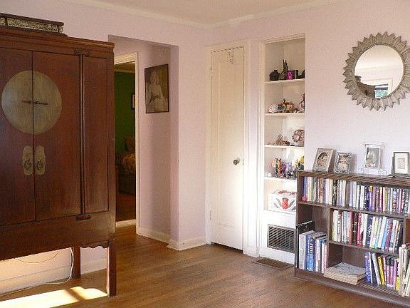 The living room holds ample pieces of furniture. The hall leads to the bedrooms and bath.