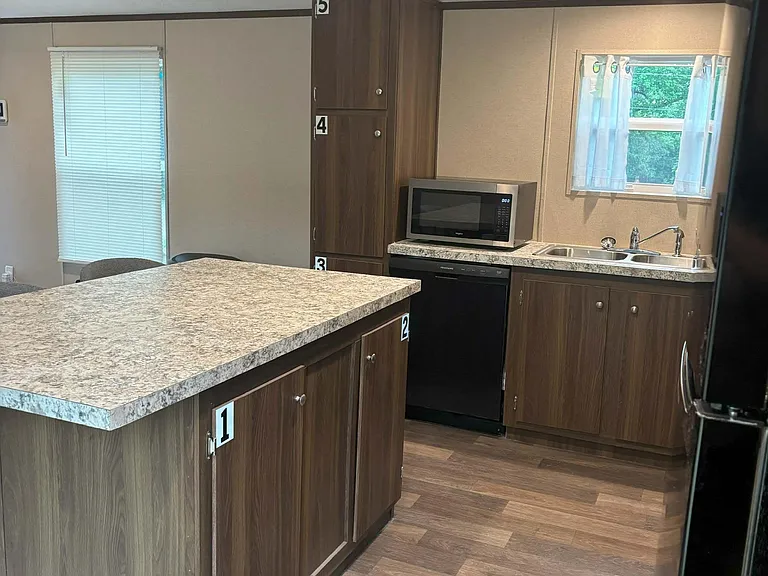 Kitchen with ample cabinet storage, large island workspace, and double-basin sink, plus dishwasher and microwave.