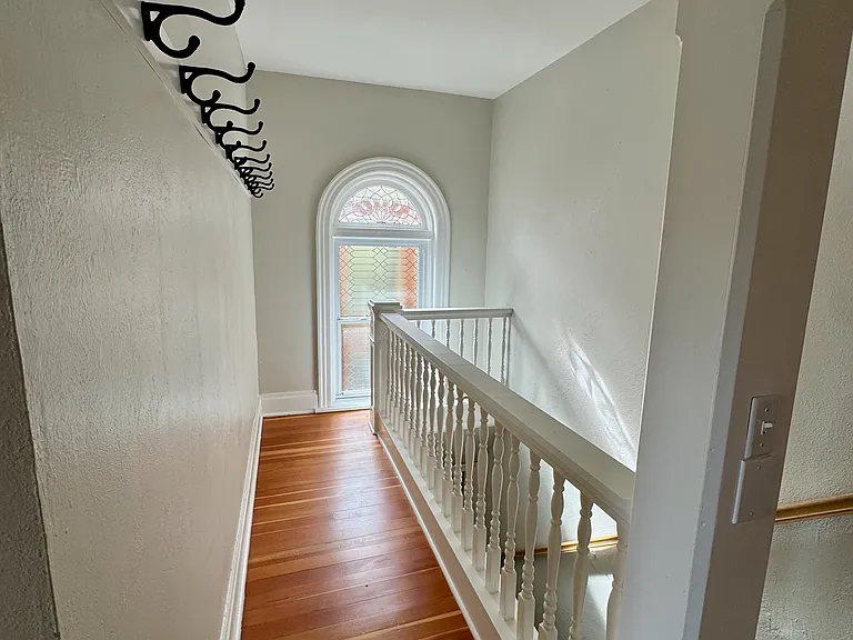 Hall landing with coat storage and arched lead glass window