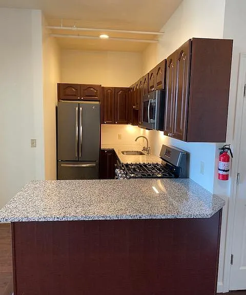 Galley style kitchen with dining bar. Stainless Steel stove (gas), refrigerator, dishwasher, microwave, and sink.