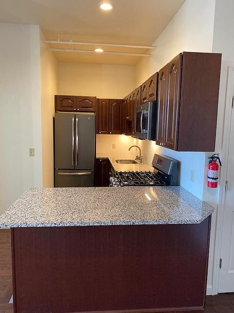 Galley style kitchen with dining bar. Stainless Steel stove (gas), refrigerator, dishwasher, microwave, and sink.