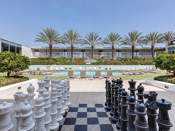 Oversized chess game board adjacent to outdoor swimming pool area.