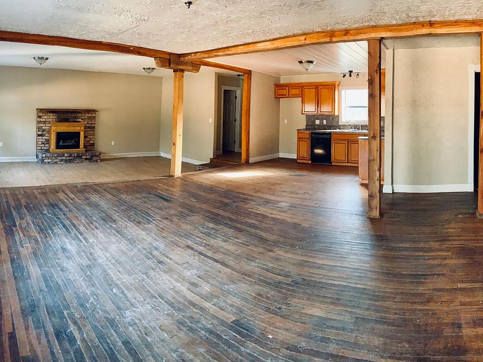 Panoramic photo of the main living space. Den and pantry on the left, kitchen and living room straight ahead. Bedrooms, Laundry and Bathroom down hall to the right.