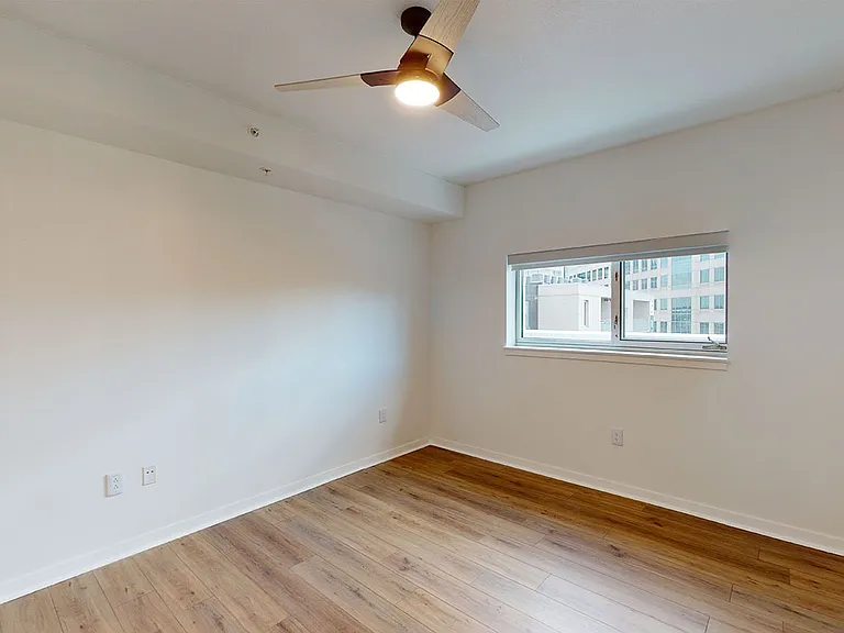 Spacious apartment bedroom with wood-style flooring.