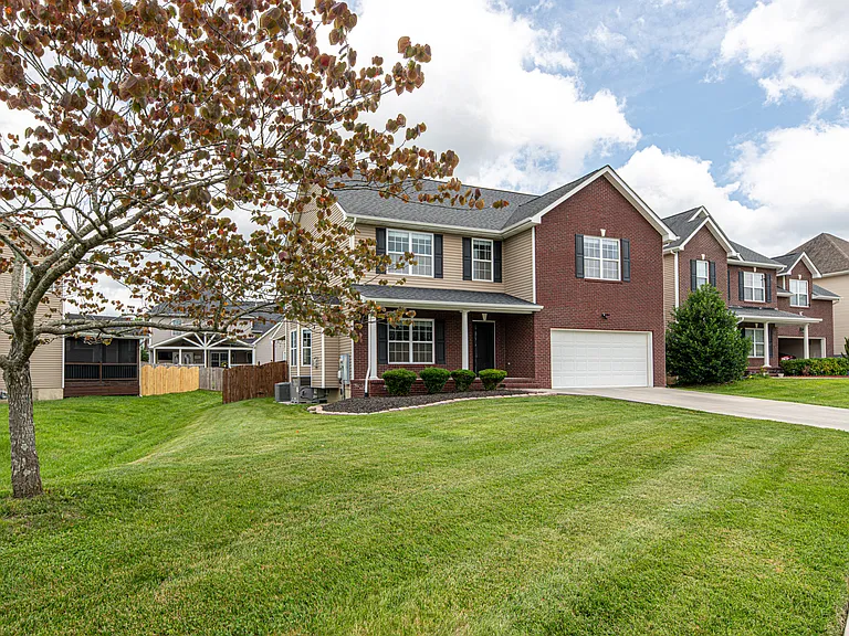 Front of property features, yard driveway, mulched area with bushes, covered porch and sidewalks