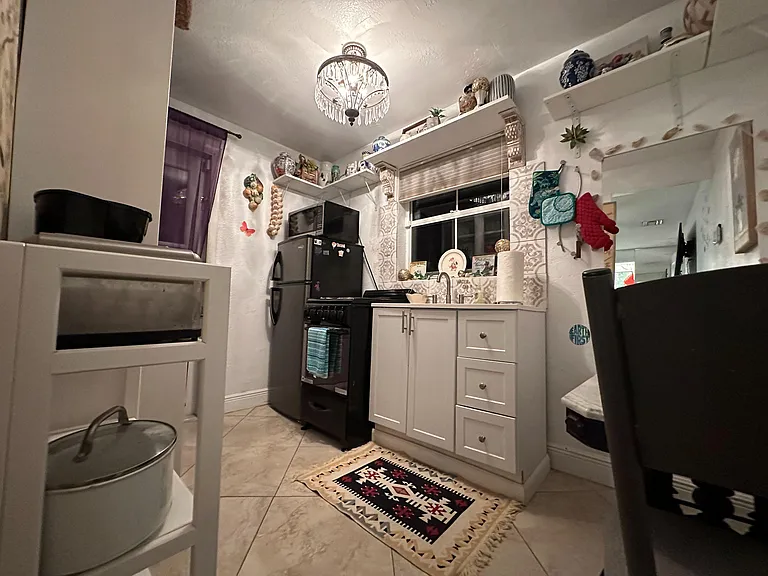 Private kitchen with ample cabinetry, open shelving, and a full appliance suite, plus a window over the sink.