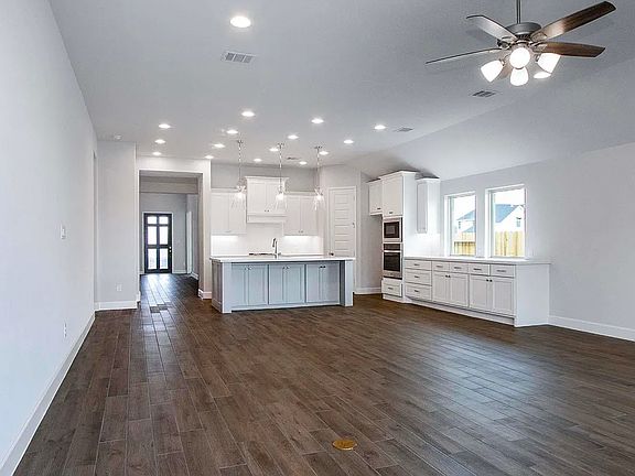 Open Concept Kitchen, Dinning, and living room with ceiling fan and projected lightings with wood pattern ceramic tiles.