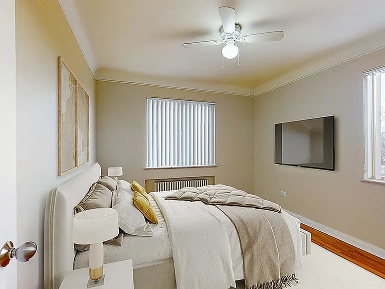 Inviting bedroom with elegant decor, featuring a cozy bed, modern ceiling fan, stylish wall art, and natural light streaming through large windows.