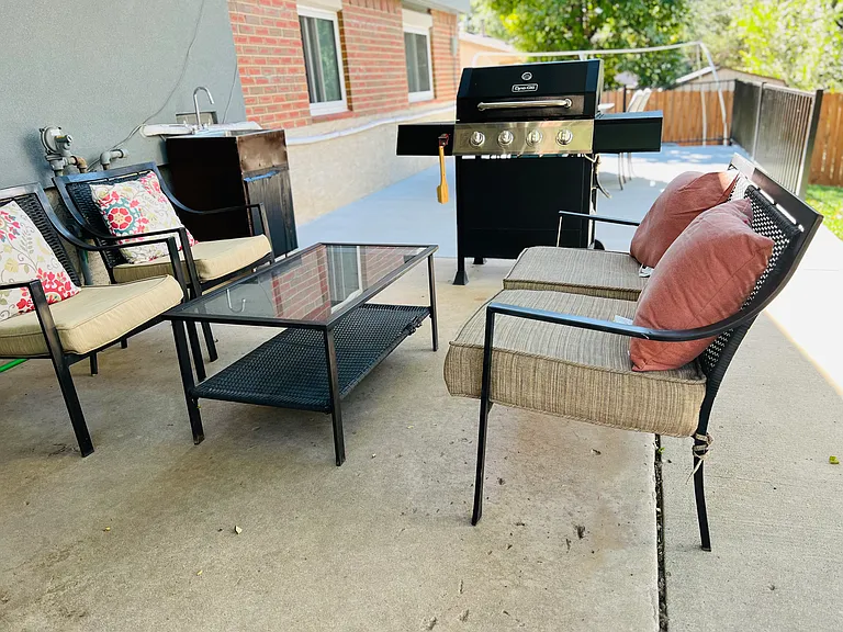 Spacious backyard patio with comfortable seating and BBQ grill, perfect for relaxing or outdoor meals.