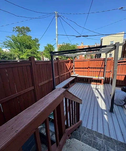 Going out from the kitche to fenced in backyard with 'L' shaped sitting area with a outlet in the middle. The parking for the car is just beyond the fence.