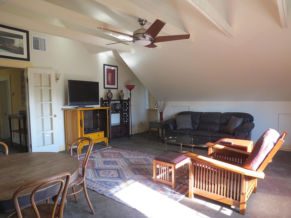 Very large front room with sofa, TV, table/chairs, and roll-top desk