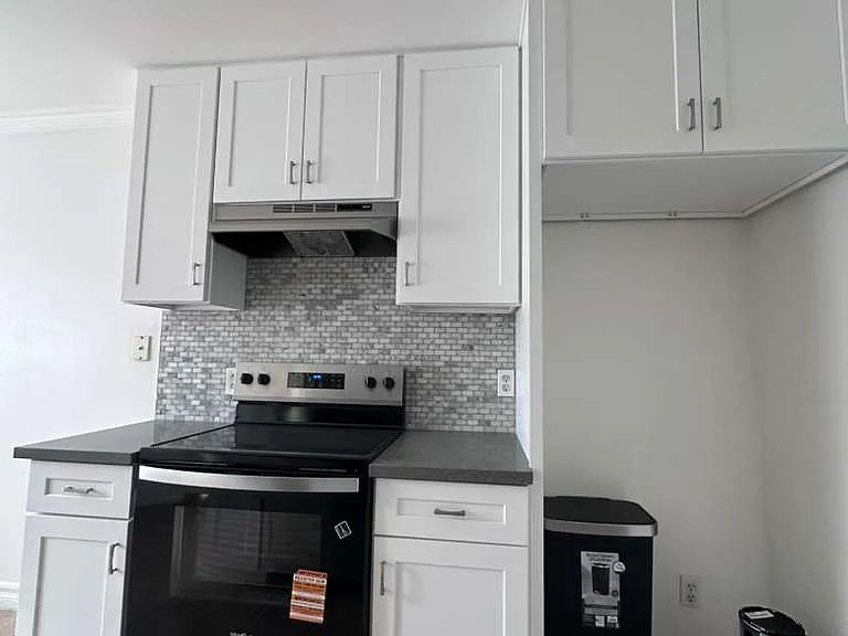 Enjoy cooking in this beautifully updated kitchen, featuring brand new, just-installed white cabinets and a brand new stainless steel range. The modern look is completed with new grey countertops and a stylish tile backsplash.