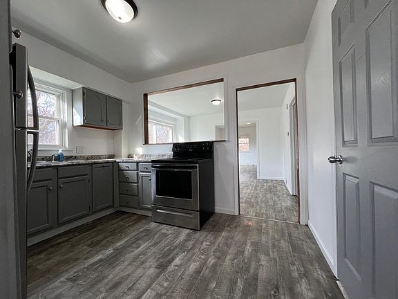 Kitchen with stainless steel appliances - refrigerator and electric stove. Open concept. Kitchen connected to dining room then living room.