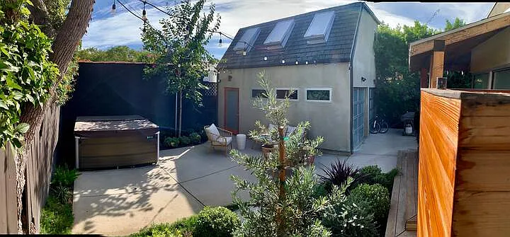 Private backyard: 7 person hot tub on the left, seating area under market lights, outdoor shower to the right