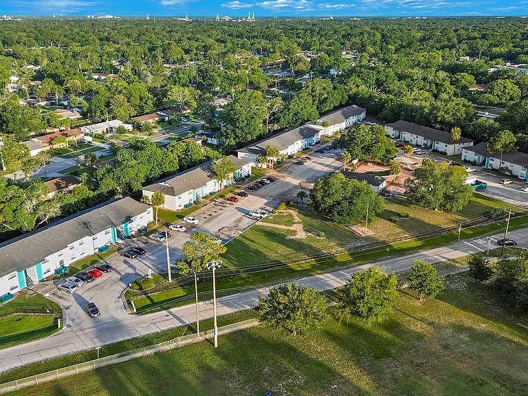 Aerial view of charming apartment complex surrounded by lush greenery and nestled in a serene neighborhood.