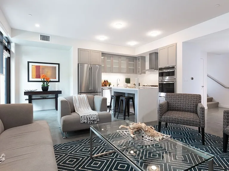 Signature Collection living and dining area with hard surface flooring and kitchen with stainless steel appliances