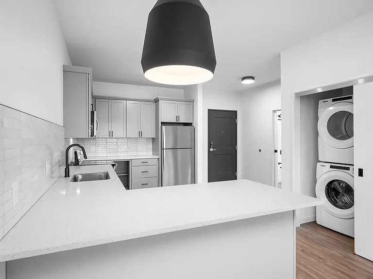 Modern kitchen featuring sleek cabinetry, elegant countertops, and integrated appliances alongside a convenient in-unit washer and dryer. Modern kitchen featuring sleek cabinetry, elegant countertops, and integrated appliances alongside a convenient in-un