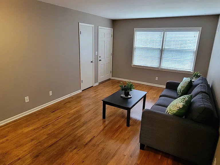 Furnished living room area with security entry locks, coat closet, refinished hardwoods, and furniture.