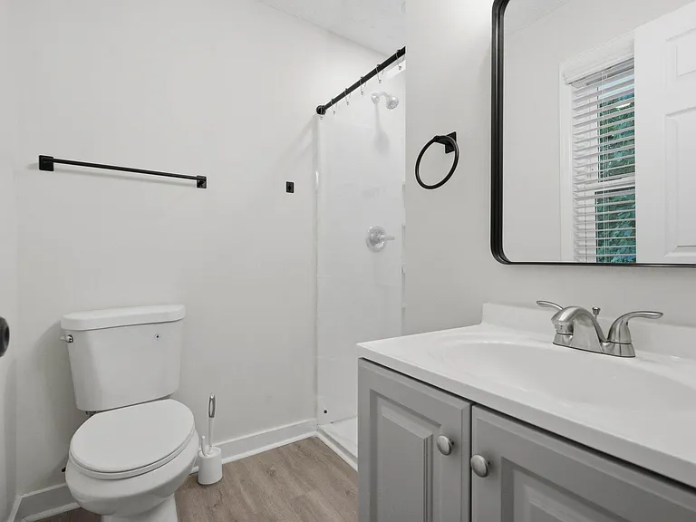 Clean full bath with tub/shower combo, vanity storage, and a window with blinds for added light and ventilation.