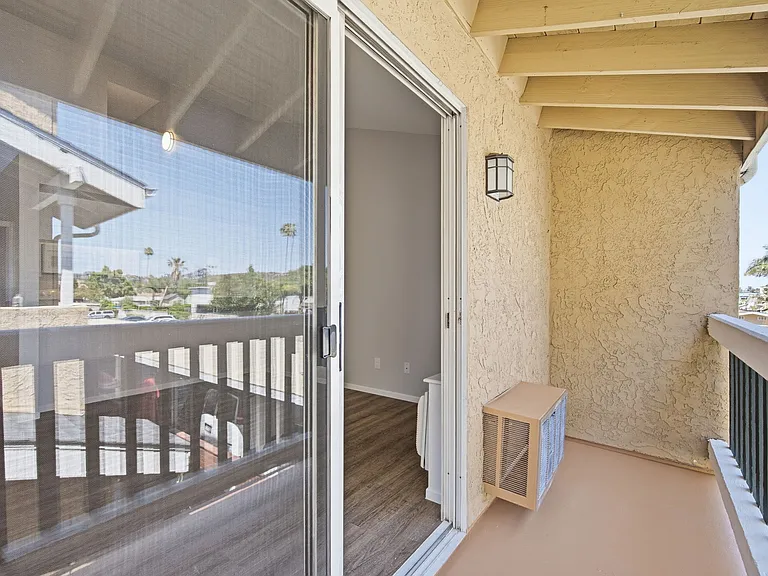 A balcony with a sliding glass door leading to a deck.