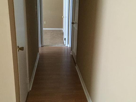 Hallway with storage closet and closet housing a/c unit and